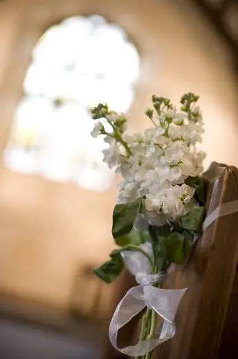 Wedding flowers on a church pew by Polly's Flowers